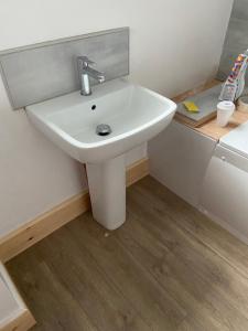 a white sink in a bathroom with a wooden floor at Lovely, recently refurbished four bedroom house.. in Hither Green
