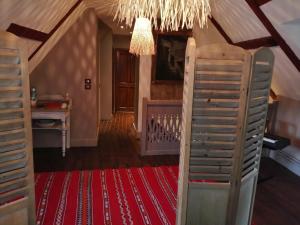 an attic room with a chandelier and a red rug at Au fil de l'eau in Cerdon