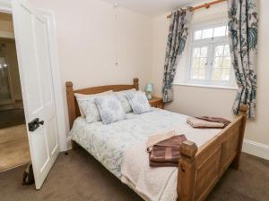 a bedroom with a wooden bed and a window at The Vale in Beaworthy