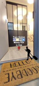 un hombre con una maleta y un cartel delante de una puerta en T4 Massy TGV by Beds4Wanderlust - 80m2 avec Terrasse et bureau - proche coulée verte - idéal Pro ou Famille, en Massy