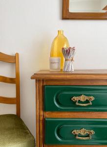 a green dresser with a yellow vase on top of it at Encosta do Sol in Canas de Senhorim