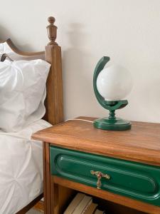 a green and white lamp on a table next to a bed at Encosta do Sol in Canas de Senhorim