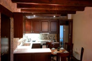 a kitchen with wooden cabinets and a small table with chairs at Petradi Residence @ Agoriani-Parnassus in Eptalofos