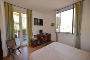 a bedroom with a bed and a desk and a window at Hotel Clelia in Deiva Marina