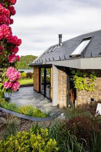 a brick house with a patio and flowers at Roselea Cottage in Luss