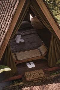 a tent with a bed and a pair of shoes in it at KAMPUNG KOPI CAMP in Pujungan