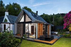 una pequeña casa con un techo negro en un patio en Roselea Cottage, en Luss