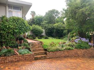 a garden with a brick staircase in front of a house at Naisiae - Lovely 1-bedroom vacation home with pool in Johannesburg