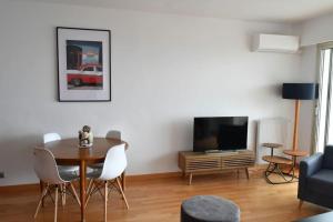 a living room with a table and a tv at French Riviera - 3 pièces, vue mer et piscine in Villefranche-sur-Mer