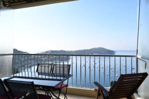 a balcony with a table and chairs and a view of the water at French Riviera - 3 pièces, vue mer et piscine in Villefranche-sur-Mer