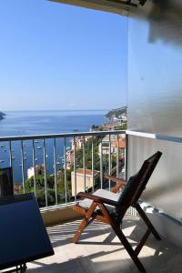 a chair on a balcony with a view of the ocean at French Riviera - 3 pièces, vue mer et piscine in Villefranche-sur-Mer