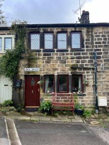 een bakstenen gebouw met een rode bank ervoor bij Charming 2-Bed Cottage in Hebden Bridge in Hebden Bridge