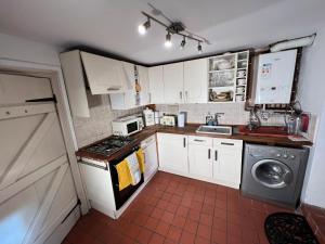 a kitchen with white cabinets and a stove top oven at Charming 2-Bed Cottage in Hebden Bridge in Hebden Bridge
