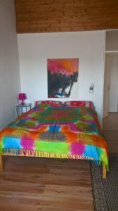 un letto colorato in una camera da letto con un dipinto sul muro di 3-Zi Atelierdachwohnung mit Bergblick Seenähe und 2 Loggia a Bernau am Chiemsee