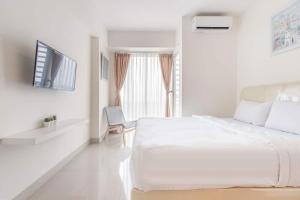 a white bedroom with a large bed and a window at RedLiving Apartemen Grand Kamala Lagoon - Kita Pro Tower Barclay North in Bekasi