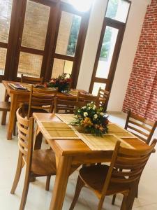 une salle à manger avec des tables en bois, des chaises et des fleurs dans l'établissement SaDev Lake Villa Bandaragama, à Bandaragama