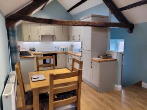 The Granary في Llanddeiniol: مطبخ صغير مع طاولة وكراسي خشبية