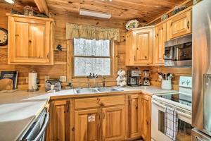 eine Küche mit Holzschränken, einem Waschbecken und einem Fenster in der Unterkunft Wandering Bear Cabin with Game Room and Hot Tub! in Sevierville