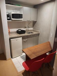a small kitchen with a wooden table and red chairs at Studio Mercure Hotel Moema - Av. Jamaris 100 in Sao Paulo