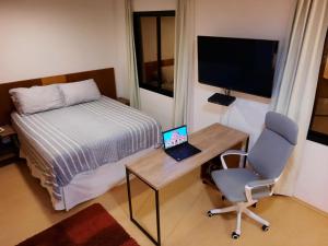 a bedroom with a bed and a desk with a laptop at Studio Mercure Hotel Moema - Av. Jamaris 100 in Sao Paulo