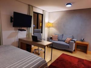 a room with a bed and a couch and a television at Studio Mercure Hotel Moema - Av. Jamaris 100 in Sao Paulo