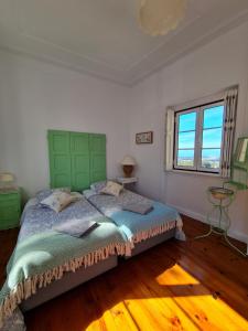 a bedroom with a bed with a green headboard and a window at Maria Saudade - Bright & Spacious Apartment with Views in the Heart of Sintra in Sintra
