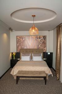 a bedroom with a large bed with a bench in it at Akacija Luxury Suites in Belgrade