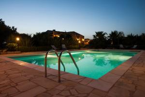 a swimming pool at night with chairs around it at Masseria Boscorotondo in Scicli