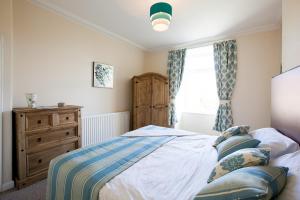 a bedroom with a bed and a dresser and a window at White Swan Cottage in Alnwick