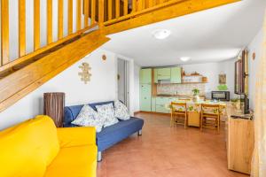 ein Wohnzimmer mit einem blauen Sofa und einer Küche in der Unterkunft Gli Ulivi Palau - Lu Maccioni in Palau