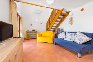 ein Wohnzimmer mit einem blauen Sofa und einem gelben Stuhl in der Unterkunft Gli Ulivi Palau - Lu Maccioni in Palau