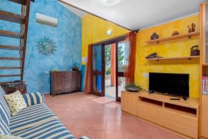 a living room with yellow walls and a flat screen tv at Gli Ulivi Palau - La Zirichelta in Palau