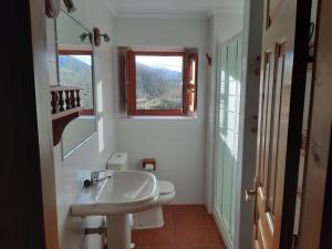 baño blanco con lavabo y ventana en Casa Rural La Roza 2 en Buelles