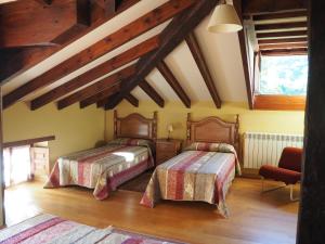 sypialnia z 2 łóżkami i sufitem z belkami stropowymi w obiekcie Casa Rural La Roza 2 w mieście Buelles
