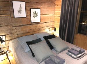 a bedroom with a wooden wall with a bed with pillows at Seitsemisen Torpat Log Cabin in Latovesi