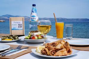a table with a plate of food and a glass of wine at Fisilanis Beachfront Hotel in Logaras