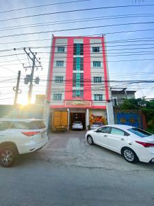 dos autos estacionados frente a un edificio rojo en KHÁCH SẠN ĐẾ VƯƠNG, en Cao Lãnh