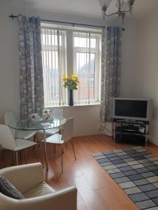 a living room with a glass table and a television at Troon Beach Town Golf Apartment Troon Ayrshire in Troon