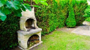 a stone oven sitting next to a green hedge at Вила Афина - Villa Afina in Balchik
