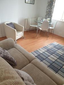 Troon Beach Town Golf Apartment Troon Ayrshire في ترون: غرفة معيشة مع أريكة وطاولة وكراسي