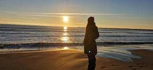 a woman standing on the beach watching the sunset at Résidence Martins in Port-la-Nouvelle