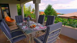 einen Tisch und Stühle auf einem Balkon mit einer Mahlzeit drauf in der Unterkunft Вила Афина - Villa Afina in Baltschik