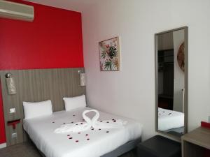 1 dormitorio con cama blanca y pared roja en Hôtel de Champagne, en Angers