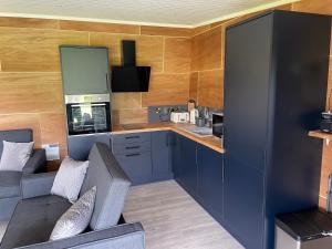 a living room with a couch and a kitchen at Famau Cabins Gwel Y mynudd in Cilcain