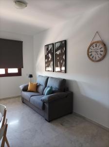 een woonkamer met een bank en een klok aan de muur bij IJD apartments 119 PARKING GRATIS Y PISCINA in Bormujos