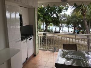een keuken met uitzicht op een balkon met een tafel bij Martial Tropiques et Martial Coco & Plage, 2 Appartements refaits à neuf vue mer, Village de vacances à Ste Anne in Sainte-Anne
