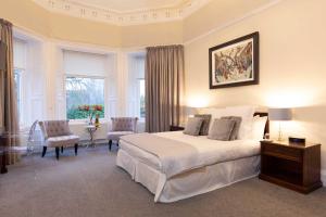 Un dormitorio con una gran cama blanca y una ventana en Fernbank House, en Aberfeldy