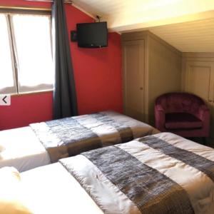 a bedroom with two beds and a tv on the wall at Logis Hôtel Restaurant Le 1050 in Saint-Agrève