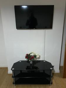 Una mesa negra con un jarrón de flores. en Lovely 2 Bedroom Apartment with free parking en Mánchester