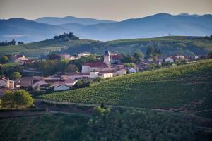 a small village on a hill with mountains in the background at La Suite in Chiroubles